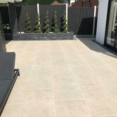 an outdoor patio with grey furniture and trees in the background