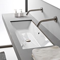 a white sink sitting under a bathroom mirror next to a towel and soap dispenser