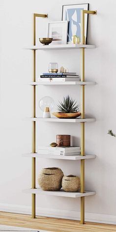 a white and gold book shelf in a living room next to a potted plant