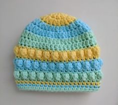 a crocheted blue and yellow hat on a white surface