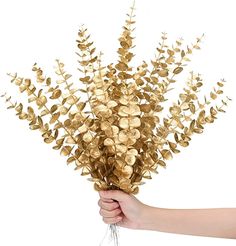 a hand holding a bunch of gold colored flowers