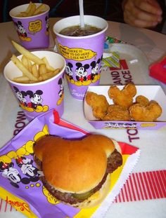 there is a hamburger and fries on the table with two cups of soda next to it