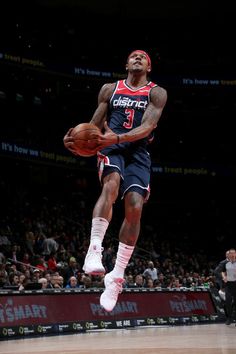 a basketball player jumping up into the air with a ball in his hand and people watching