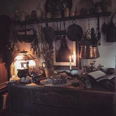 an old fashioned kitchen with many pots and pans on the shelf above it, lit by a candle