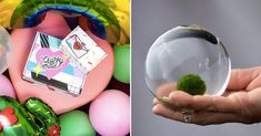 a hand holding a glass ball with a small green plant in it next to an assortment of balloons