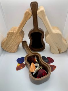 several wooden instruments are arranged in a display case on a white surface, including one ukulele and the other