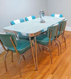 a dining room table with blue chairs and a silver vase on top