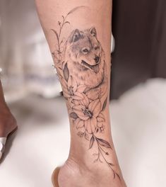 a woman's foot with a wolf and flowers tattoo on her left side leg