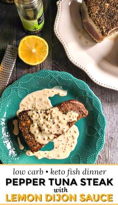 a blue plate topped with meat covered in gravy next to lemons and bread