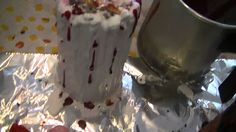 a piece of cake sitting on top of tin foil next to a metal cup and saucer