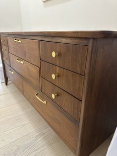 a wooden dresser with brass handles in a room