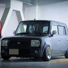 a small black car parked in front of a white wall