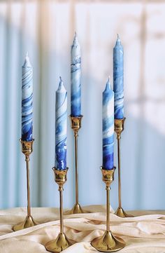 three blue candles sitting on top of a table next to two gold candelabras