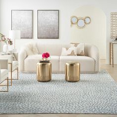 a living room with white furniture and gold accents on the walls, along with blue rugs