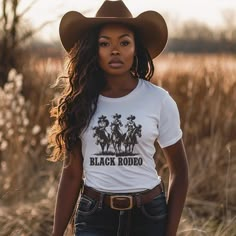 Dive into the essence of Western elegance with our 'Black Rodeo Unisex Tee,' a fashion statement that celebrates heritage and the adventurous spirit of three stunning Black women on their majestic rides. Perfect for individuals passionate about Western equestrian culture, heartland melodies, and the vibrant traditions of rodeo, this tee is a tribute to the enduring strength of cowgirl legends. Crafted from premium soft materials for ultimate comfort and durability, it's ideal for any setting, from country outings to casual gatherings. Offering a range of sizes to ensure a perfect fit for everyone, this versatile tee bridges modern fashion with traditional homage, making it a must-have for those who cherish the legacy of Black cowgirls and the timeless charm of Western culture, all while em Cattle Barons Ball Outfit, Women Cowboy Outfits, Rodeo Outfits For Women Black, Country Outfit Black Women, Band Merch Tops With Custom Print, Fitted Band Merch Shirt, Black Cowgirl Outfits For Women, Cali Cowgirl, Black Rodeo Outfits For Women