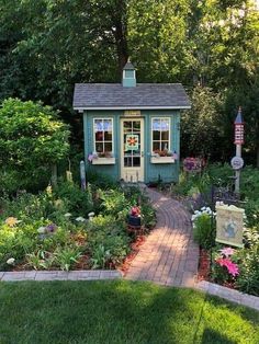 a small garden shed in the middle of a yard with flowers and plants around it