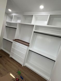 an empty room with white shelves and drawers in the middle, including construction tools scattered on the floor