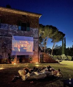 an outdoor movie is being projected on the screen in front of a large brick building