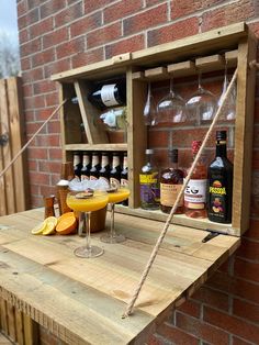 a wooden table topped with glasses filled with drinks next to a wall mounted wine rack