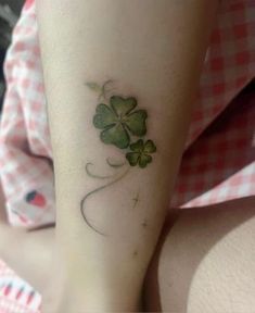 a woman's leg with a four - leaf clover tattoo on her left arm