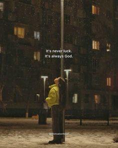 a woman standing under a street light in the rain with her head up against a pole