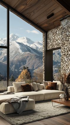 a living room filled with lots of furniture next to a large window covered in snow capped mountains