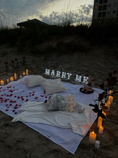 a white blanket with candles and flowers on it in front of a sign that says marry me