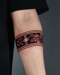 a woman with a tattoo on her arm is wearing a black and red flowered bracelet