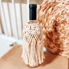 an empty bottle sitting on top of a wooden table next to a roped basket