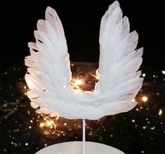 a cake with white feathers on it sitting on a table next to a lite up background