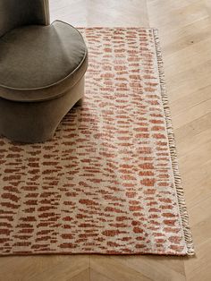 a chair sitting on top of a wooden floor next to a brown and white rug