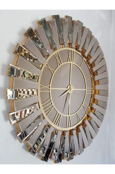 a clock that is on the wall with many mirrors around it's face and hands