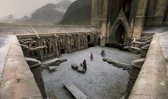 some people are standing in the middle of a courtyard with mountains in the back ground