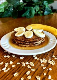 a stack of pancakes with banana slices and peanut butter on top sitting on a wooden table