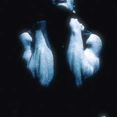 a man with his hands on his chest in the dark