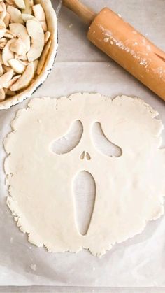 an uncooked pizza dough next to a rolling pin and bowl of sliced almonds