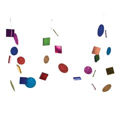 a group of colorful objects hanging from strings on a wall in front of a white background