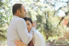 a man and woman embracing each other in front of trees