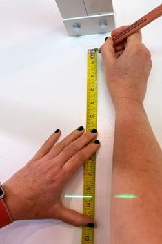 a woman is measuring the height of her arm with a tape measure on top of it