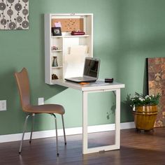 a laptop computer sitting on top of a white desk in front of a green wall