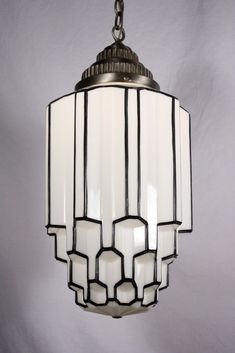 a light fixture hanging from a chain on a white wall with black and white trim