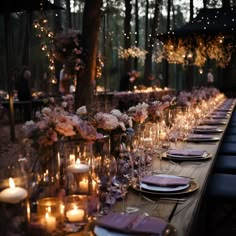 a long table is set with candles and plates for an elegant dinner party in the woods