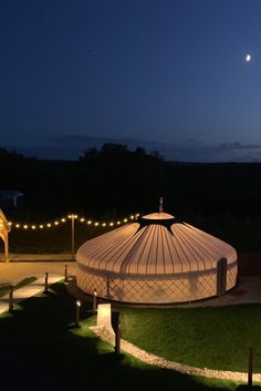 a large white tent sitting on top of a lush green field under a night sky