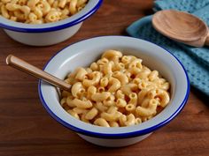 two bowls filled with macaroni and cheese on top of a wooden table