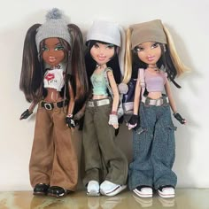 three dolls standing next to each other in front of a white wall and wearing hats