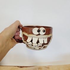 a hand holding a coffee cup with fake teeth on it's face and mouth