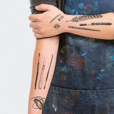 a woman's arm with tattoos on it, including an arrow and arrows in black ink