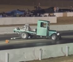 an old green truck is being towed on the track