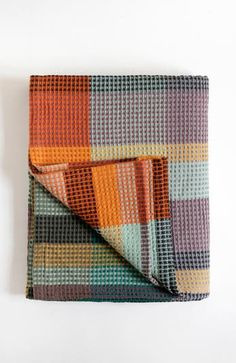 a multicolored blanket folded on top of a white surface