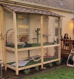 a woman is sitting on the porch in front of her house with an animal cage